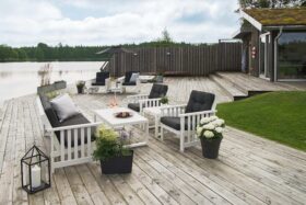 Hillerstorp Gotland Loungegrupp vit. Gruppen består av 3-sitssoffa, två fåtöljer och loungebord. På bilden med mörkblå dynor.